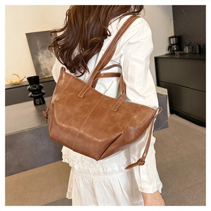Detail of deep brown retro leather tote bag worn by a model in a minimalist home setting