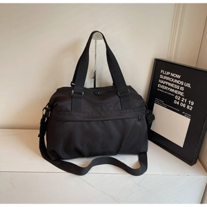 Dettaglio dei manici in nylon e della tracolla rimovibile sulla borsa da viaggio nera