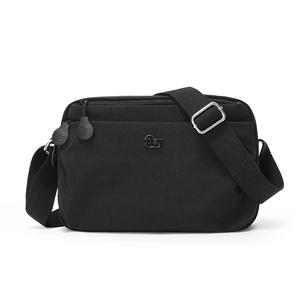 Detail view of black nylon crossbody bag showing the front zipper pocket and logo