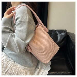 Pink bucket bag with unique wave texture and wide shoulder strap on a model's outfit