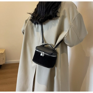 Detail of black mini crossbody bag featuring a mix of lychee leather and matte suede textures