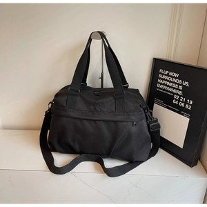 Dettaglio della borsa da viaggio in nylon nero con ricamo del brand e tracolla