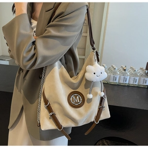 Dettaglio borsa hobo beige con finiture in pelle marrone e ciondolo a nuvola di peluche