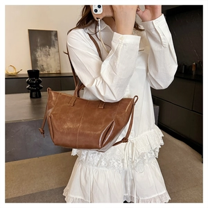 Detail of vintage brown tote bag with oil-wax leather texture and side drawstrings