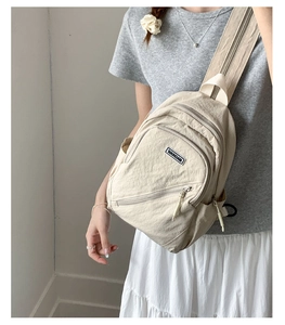 Detailed view of beige nylon crossbody bag with multi-pocket layers and adjustable strap