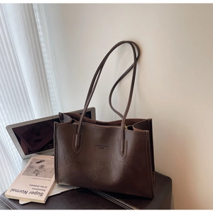 Close-up of brown leather tote bag with Fashion Trend text and modern laptop props