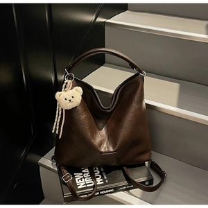 Detail of a dark brown pebble grain faux leather tote bag on modern design books
