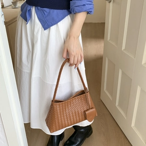 Dettaglio della borsa a mano in pelle intrecciata marrone con mini pochette coordinata