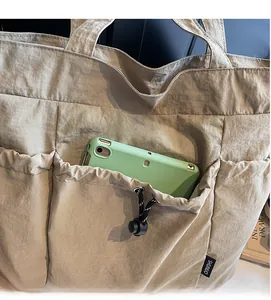 Detail of khaki nylon tote bag showing durable side pocket with functional drawstring toggle
