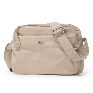 Detail view of beige nylon crossbody bag featuring multi-zipper pockets and wide canvas strap