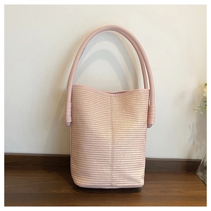 Detailed close-up of light pink woven bucket bag with smooth leather handle design