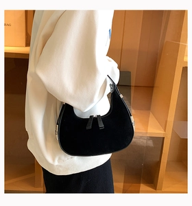 Detail of black suede crescent bag featuring double zipper closure and metallic buckle