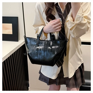 Detail of glossy black patent leather tote bag with vertical stripes shown on a model