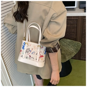 Vue détaillée du sac cabas blanc à graffitis avec motifs colorés et boucles dorées chic