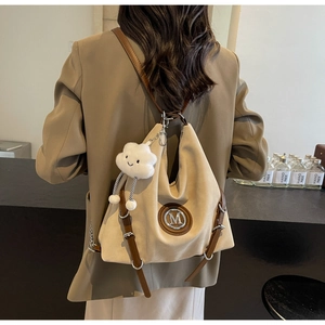 Dettaglio della borsa tote in tela con tracolla in pelle marrone e ciondolo a nuvola