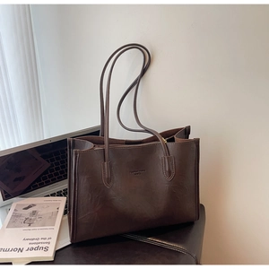 Detail of dark brown tote bag showing embossed fashion trend text and leather texture