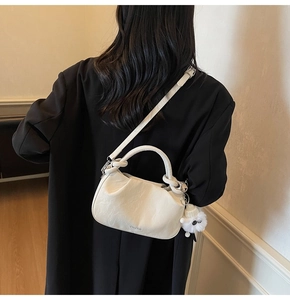 Detail of off-white ruched leather bag with plush charm and adjustable shoulder strap