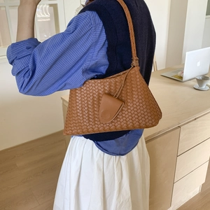 Dettaglio di una borsa sottobraccio in pelle intrecciata marrone con trama intrecciata