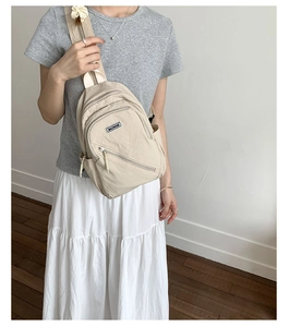 Detailed view of beige nylon crossbody chest bag with adjustable strap on model