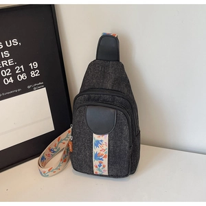 Close-up of dark grey denim chest bag featuring colorful floral embroidered wide shoulder strap