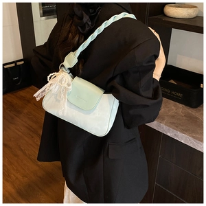 Detail of mint green underarm bag with woven strap, pearl pendant and lace bow
