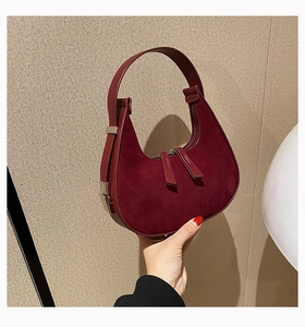 Detail of burgundy suede half-moon bag with silver hardware and double zippers