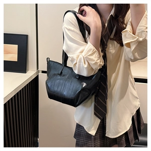 Side view of a vintage black textured tote bag with glossy finish on a female model