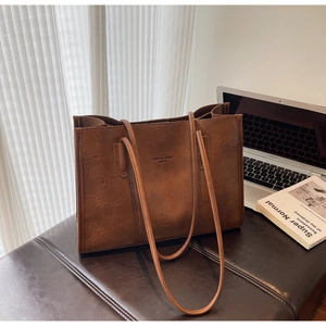 Detail of a brown leather tote bag with embossed fashion trend text in a home office setting