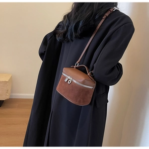 Detailed side view of brown mini box bag in textured leather and suede on black coat