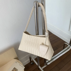 Dettaglio borsa a tracolla intrecciata color crema con mini borsellino decorativo