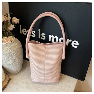 Close-up of pink woven bucket bag texture with durable leather handle on elegant backdrop