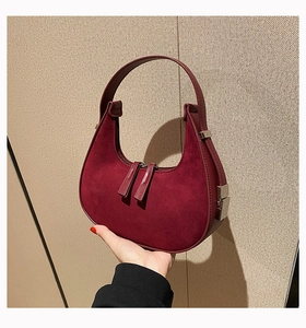 Detail of wine red crescent bag featuring matte suede and smooth leather stitching