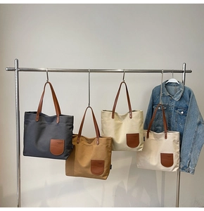 Dettaglio di grandi borse tote in tela in quattro colori con manici e tasche in pelle pregiata