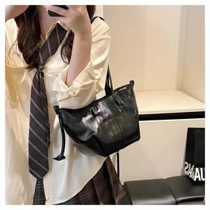 Detail of black glossy tote bag with pleated texture and stylish tassel decoration