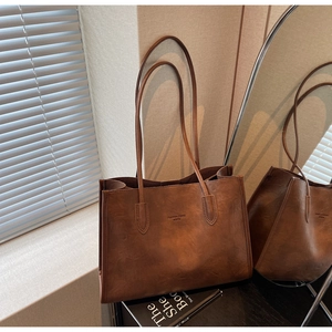Detail view of brown vintage tote bag with matte leather texture and brand lettering