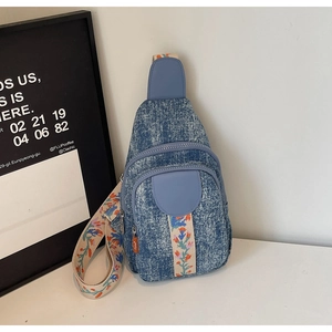 Detail of floral embroidery and faded denim texture on a multi-zip crossbody bag