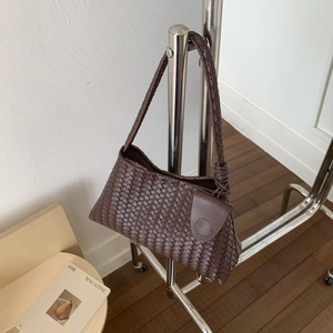 Dettaglio della borsa a spalla intrecciata marrone con tasca rotonda sulla tracolla