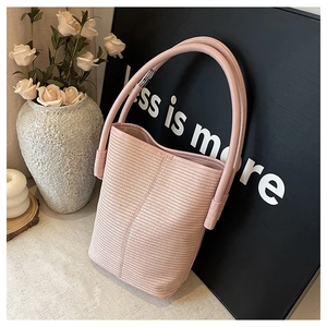 Detail of pink woven bucket bag with smooth leather handle and herringbone weave texture