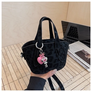 Close-up of black leopard print mini bag with pink heart and key charm accents