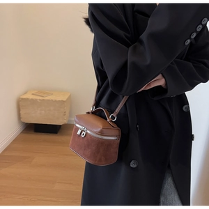 Detailed macro view of brown box crossbody bag with lychee leather and suede texture