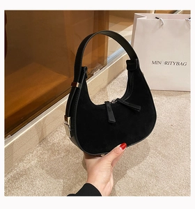 Detail of black suede hobo bag featuring dual zippers and metallic buckle adjustment