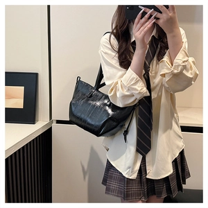 Detailed view of glossy pleated black PU leather tote bag worn with a stylish outfit