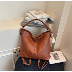 Detail of caramel lychee grain leather tote bag with plush charm and embossed logo