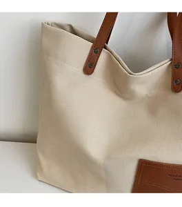 Dettaglio della borsa tote in tela con manici in pelle marrone e rivetti di rinforzo