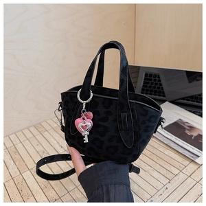 Macro detail of black leopard print tote bag with heart pendant and adjustable strap