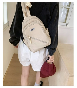 Detail view of the beige canvas chest bag with adjustable strap and brand label