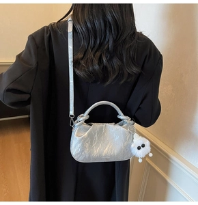 Silver metallic cloud bag with pleated texture and plush charm shown on person