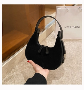 Detailed close-up of a black hobo bag showing suede texture and silver buckle accents
