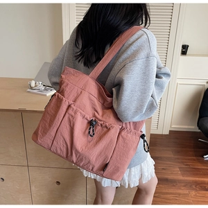 Detailed back view of a dusty pink nylon tote bag with functional pockets and drawstring
