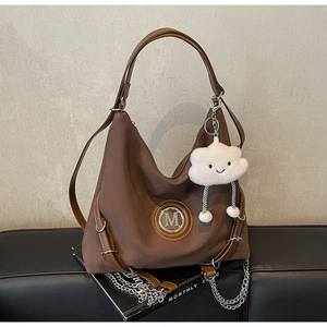 Dettaglio di una borsa hobo marrone con logo M metallico e ciondolo a forma di nuvola soffice
